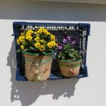 spring flowers in two plantpots which have been decorated with string, on a window sill in the sun